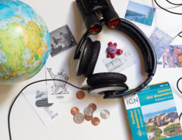 Casque audio entouré d'éléments liés au voyage comme un globe et des tickets de visites